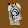 Mochila transportadora ANIMALZO tipo cápsula espacial con ventana panorámica y gato blanco en el interior